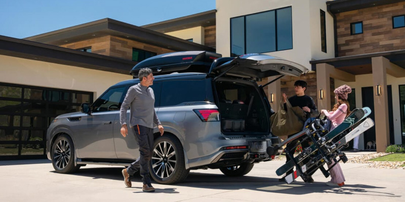 2026 INFINITI QX80 with family loading ski equipment.
